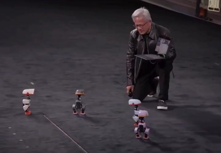Jensen Huang GTC Berlin sahnesinde diz çökmüş, Microduck robotlarını izliyor